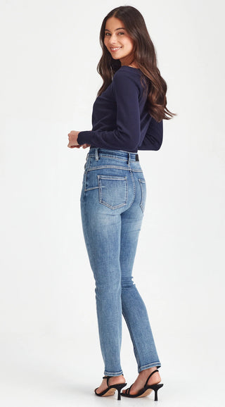 Woman wearing a navy blue sweatshirt and slim-fit blue jeans with black strap heels.