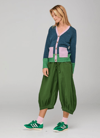 Woman wearing a color-block knit cardigan, green balloon pants, and green sneakers.