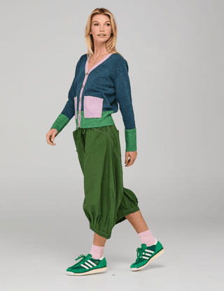 Woman wearing a color-block cardigan, green balloon pants, and green sneakers.