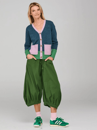 Woman wearing a color-block cardigan and green balloon pants with green sneakers.