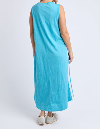 Back view of a woman wearing a sleeveless turquoise maxi dress with white side stripes.