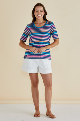 Woman wearing a colorful striped t-shirt and white casual shorts.