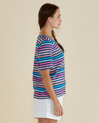 Woman wearing a colorful striped short sleeve t-shirt and white shorts.
