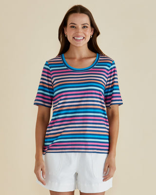 Woman smiling in a colorful striped short sleeve t-shirt and white shorts.