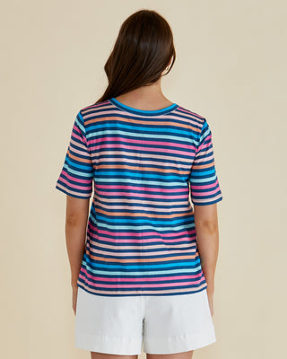 Woman wearing a colorful striped short sleeve t-shirt and white shorts.