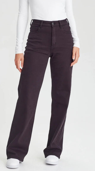 Woman wearing dark charcoal wide leg trousers and a white long sleeve top.