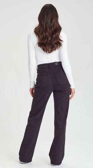 Woman wearing a white long sleeve top and dark brown wide leg trousers from behind.