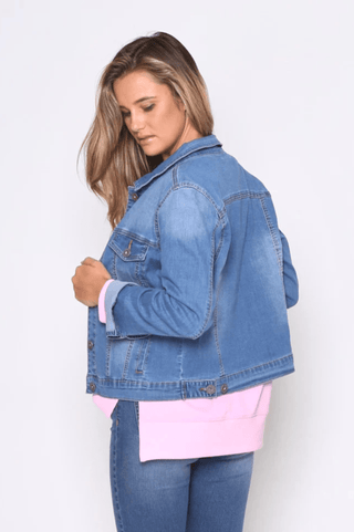 Woman wearing a blue denim jacket over a pink top and matching blue jeans.