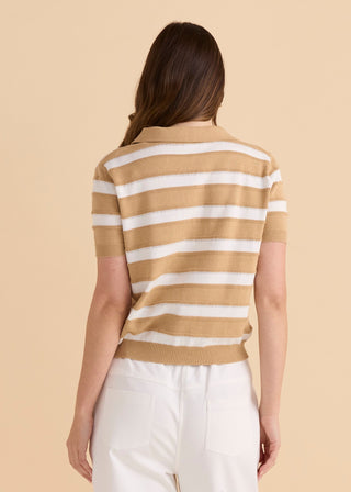 Woman wearing a tan and white striped short sleeve polo knit shirt and white pants.