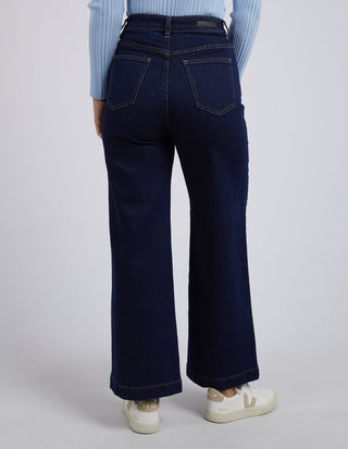 Back view of a woman wearing dark blue wide-leg jeans and white sneakers