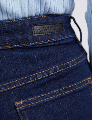 Close-up of dark blue FXW DENIM jeans waistband and back pocket with gold stitching.