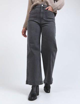 Woman wearing high-waisted wide-leg grey jeans and black heeled boots