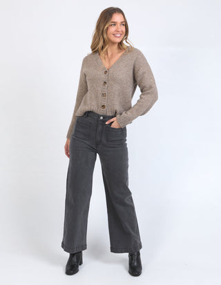 Woman wearing a beige button-up cardigan, charcoal wide-leg jeans, and black ankle boots.