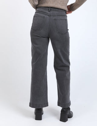 Rear view of a woman wearing dark grey wide-leg jeans and black platform boots.