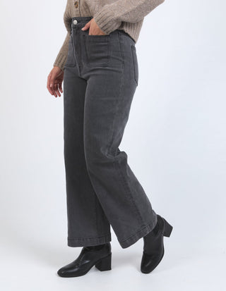 Woman wearing high-waisted charcoal grey wide leg jeans and black leather ankle boots
