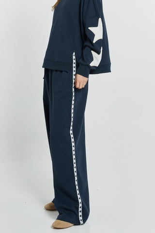 Navy blue sweatshirt with white star details and matching wide-leg joggers with star trim.