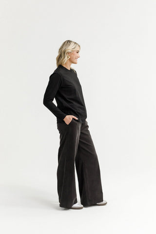 Woman wearing a black long sleeve top and dark wide leg lounge pants.