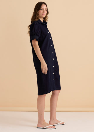 Woman wearing a navy blue short sleeve button-down denim shirt dress and white flip flops