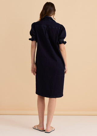 Back view of a woman wearing a navy blue short sleeve denim shirt dress.