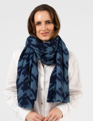Woman wearing a blue and navy patterned wool scarf and a white button-up shirt.