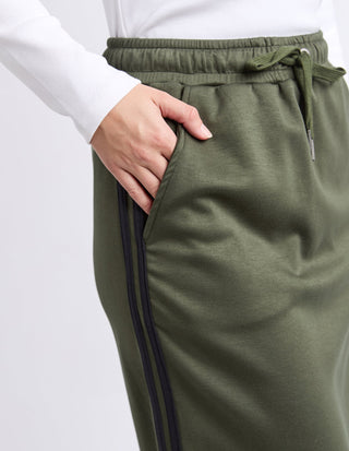 Close-up of a woman wearing olive green joggers with a side stripe and drawstring waist.