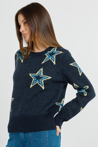 Woman wearing a navy blue knit sweater with large light blue and yellow star patterns.