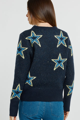 Woman wearing a navy blue knit sweater featuring large blue and yellow star patterns.