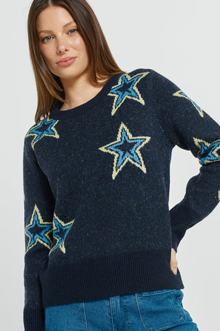 Woman wearing a navy blue knit sweater with large blue and yellow star patterns.