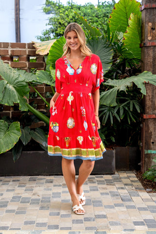 Woman wearing a red short sleeve V-neck summer dress with tropical fruit prints.