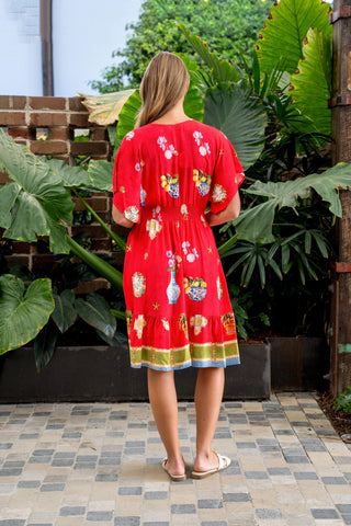 Woman wearing a red floral print midi dress with short sleeves standing outdoors.