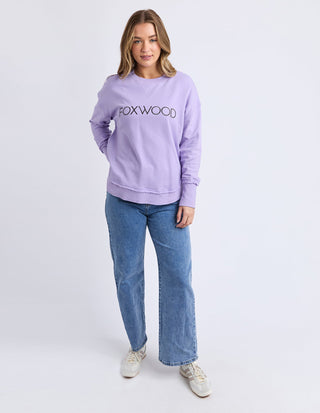 Woman wearing a lilac Foxwood sweatshirt and blue wide-leg jeans