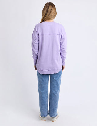 Woman wearing a lavender long sleeve sweatshirt and blue denim jeans from the back.