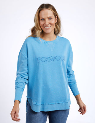 Woman wearing a blue Foxwood long sleeve sweatshirt and denim jeans