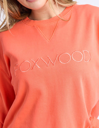 Close-up of a woman wearing a coral Foxwood embroidered sweatshirt.