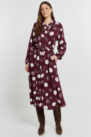Woman wearing a burgundy long-sleeve midi shirt dress with white patterns and brown boots.