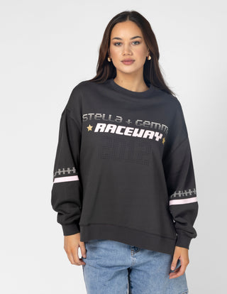 Woman wearing a black oversized graphic sweatshirt with white Raceway text and pink stripes.