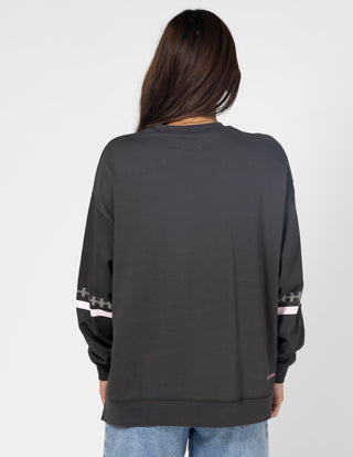 Back view of a woman wearing a charcoal grey long sleeve sweatshirt with pink stripe detail.