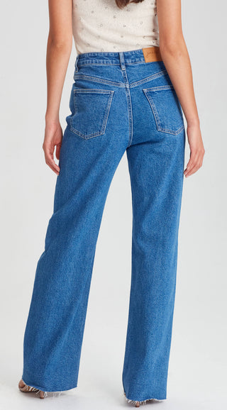 Rear view of a woman wearing blue wide-leg denim jeans with a raw hem.