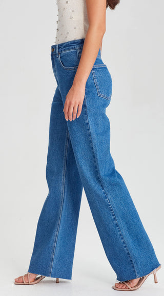 Woman wearing high-waisted wide-leg blue jeans and beige strappy heels.