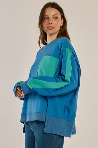 Woman wearing a blue and green color-block oversized sweatshirt and blue jeans