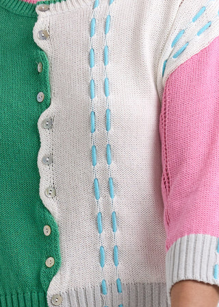 Multi-colored knit cardigan with green, white, and pink panels and blue decorative stitching.