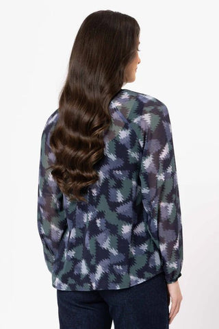 Woman wearing a long-sleeve patterned blouse with a dark geometric print.