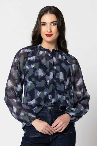 Woman wearing a dark blue and green ikat pattern long sleeve blouse and denim jeans