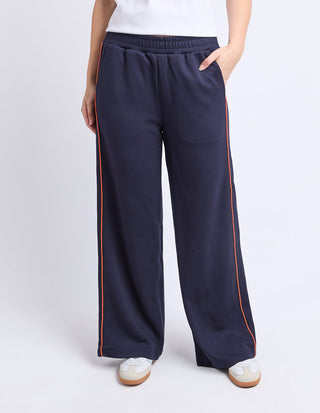 Navy blue wide-leg lounge pants with orange side stripe detailing.