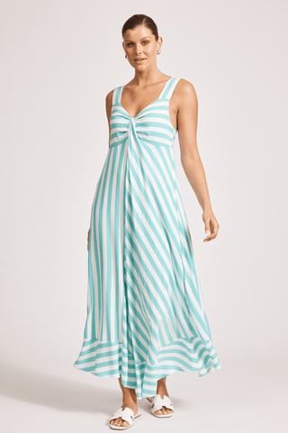 Woman wearing a teal and white striped sleeveless maxi dress and white sandals.