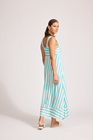 Woman wearing a blue and white striped maxi dress and white sandals.