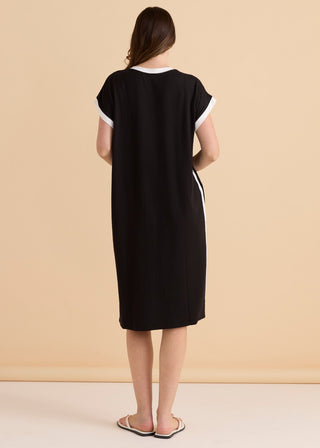 Back view of a woman wearing a black midi dress with white trim and side stripe details.
