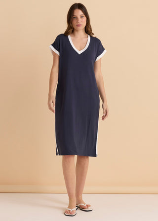 Woman wearing a navy blue v-neck midi dress with white trim accents.