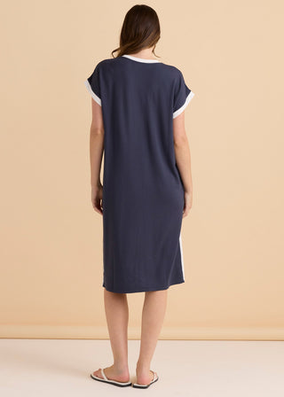 Back view of a woman wearing a navy blue t-shirt style midi dress with white trim.