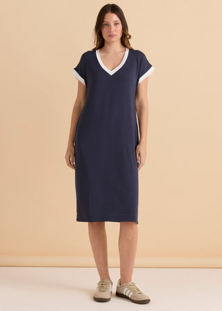 Woman wearing a navy blue V-neck midi dress with white trim.